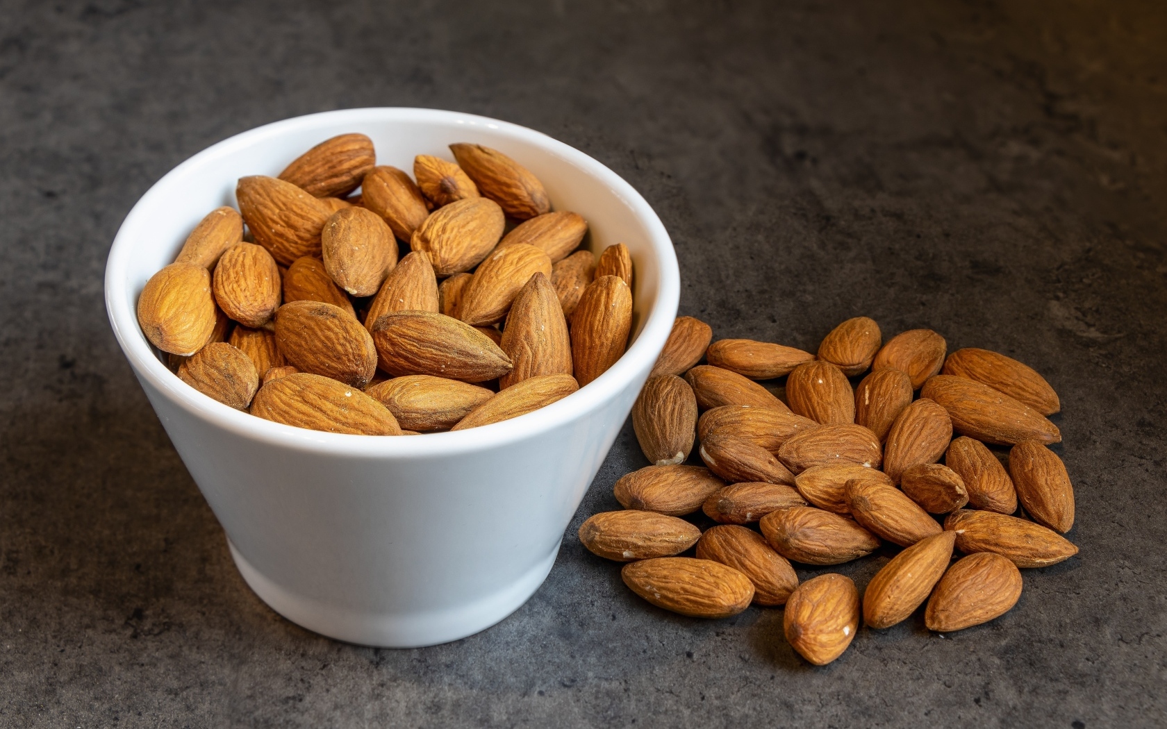 Миндальные орехи в белой пиале на столе