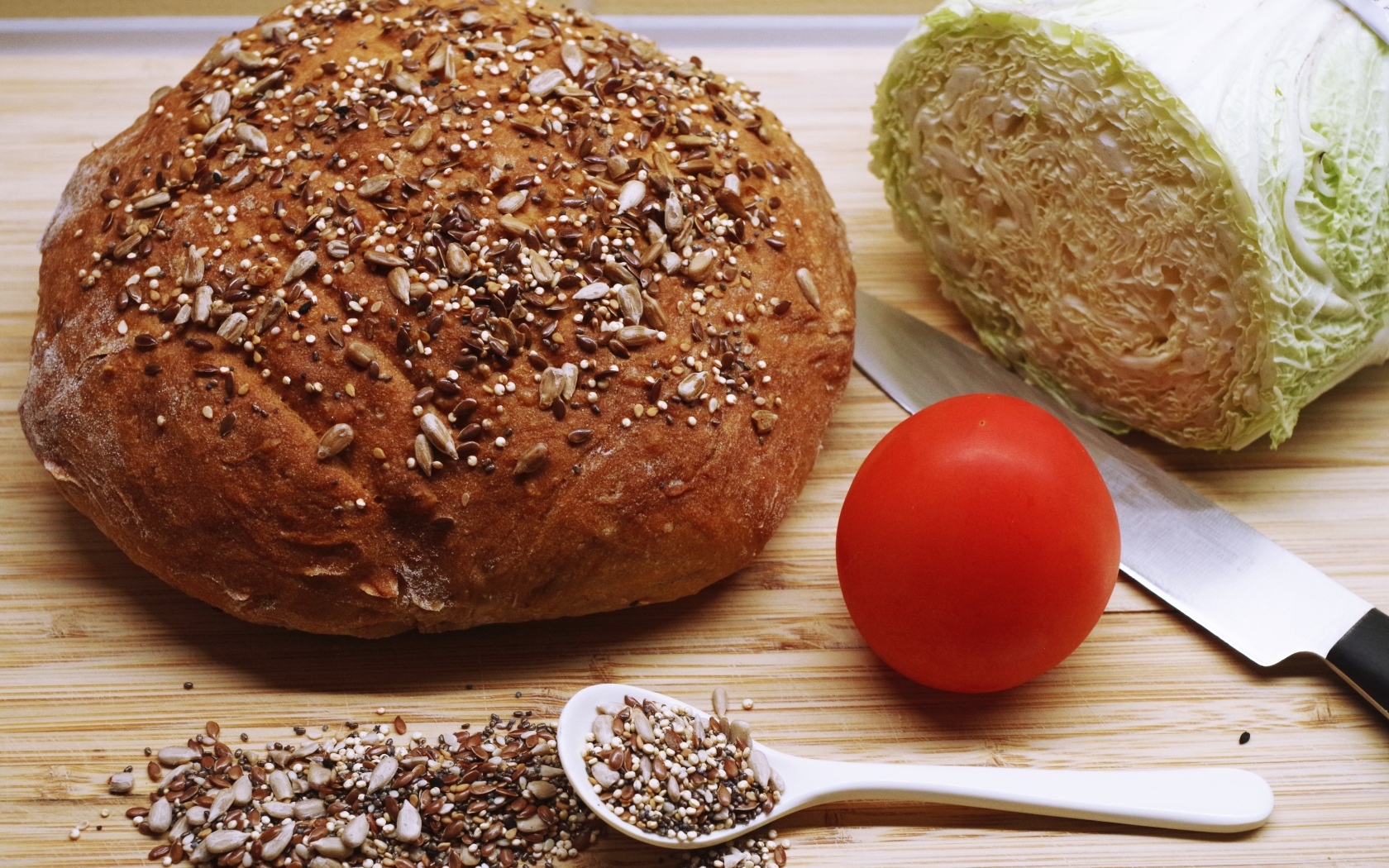 Буханка хлеба на столе с капустой и помидором