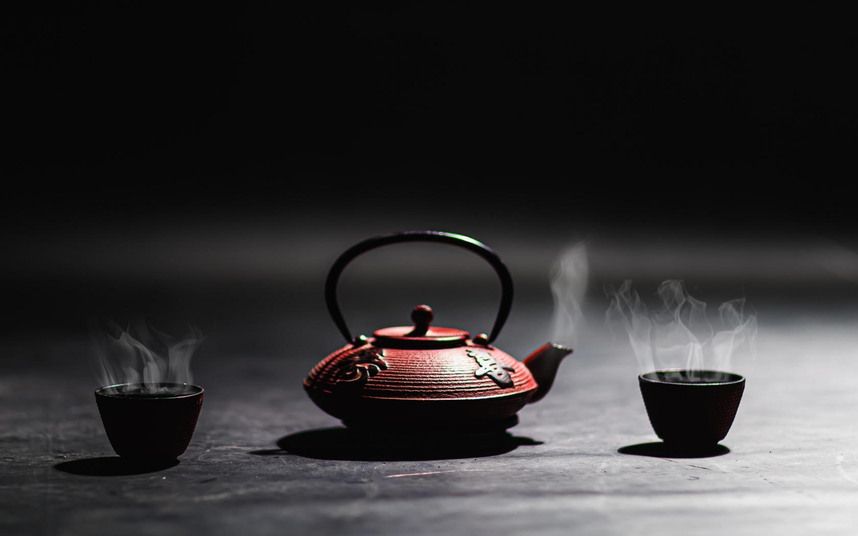 Чайник с горячим чаем на черном фоне