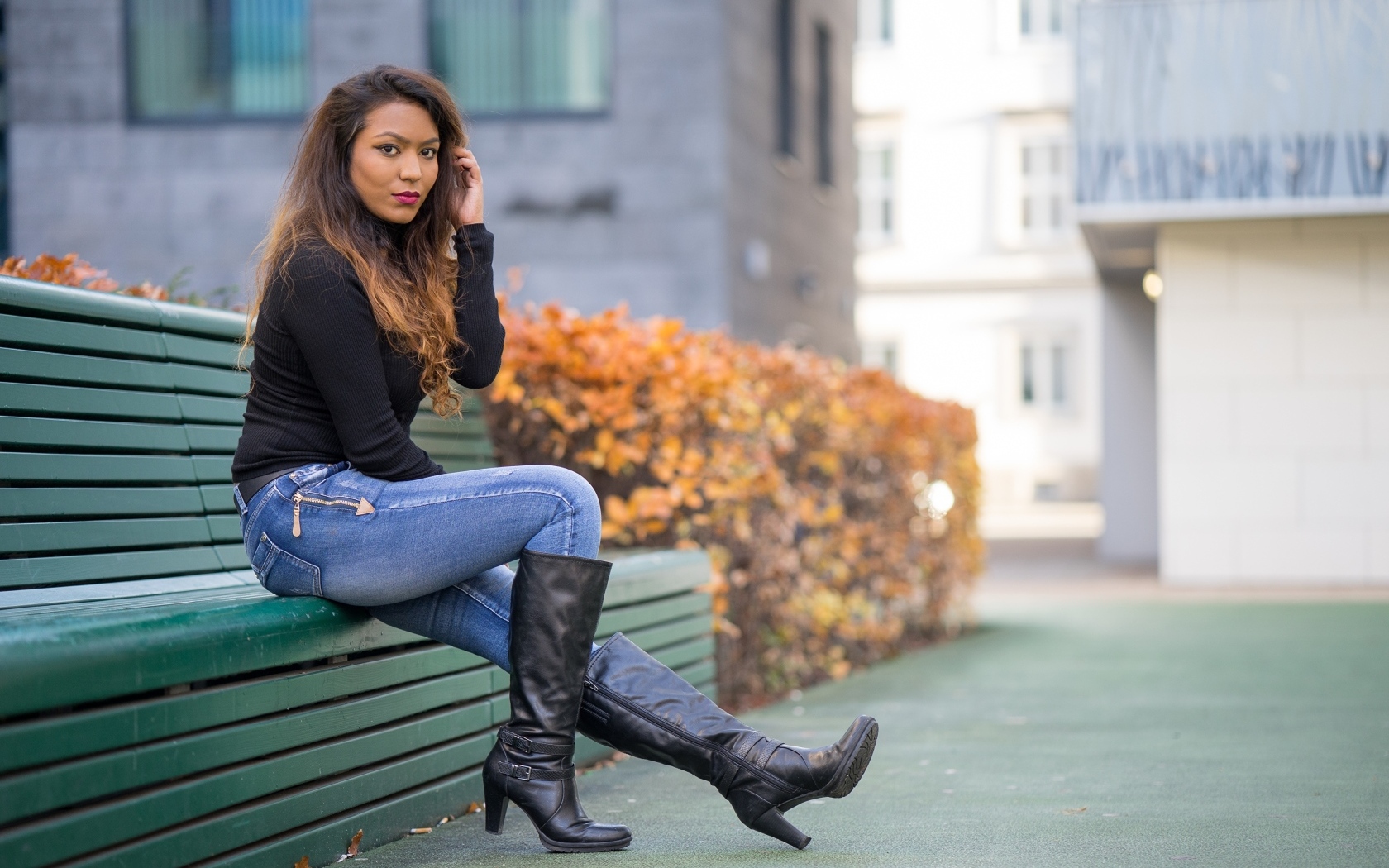 Брюнетка в синих джинсах сидит на лавке