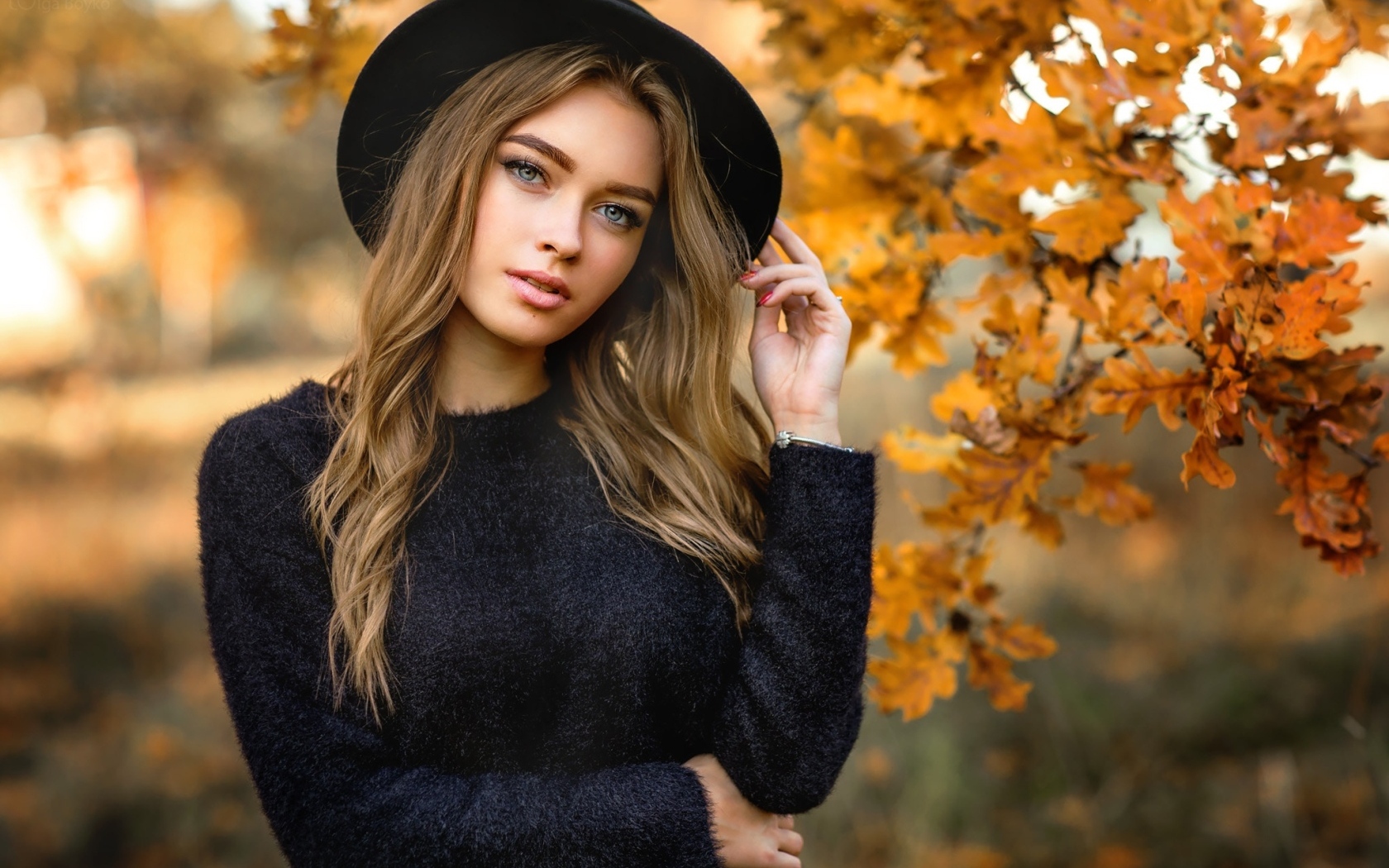 Девушка в черной шляпе стоит у дуба