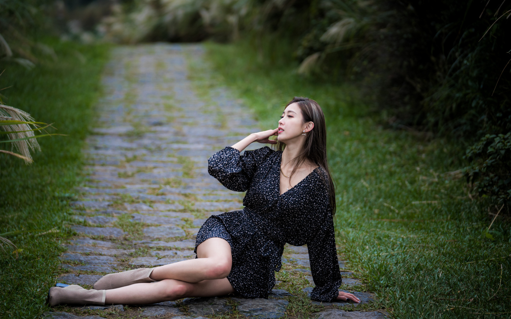 Девушка азиатка в платье лежит на дороге в парке