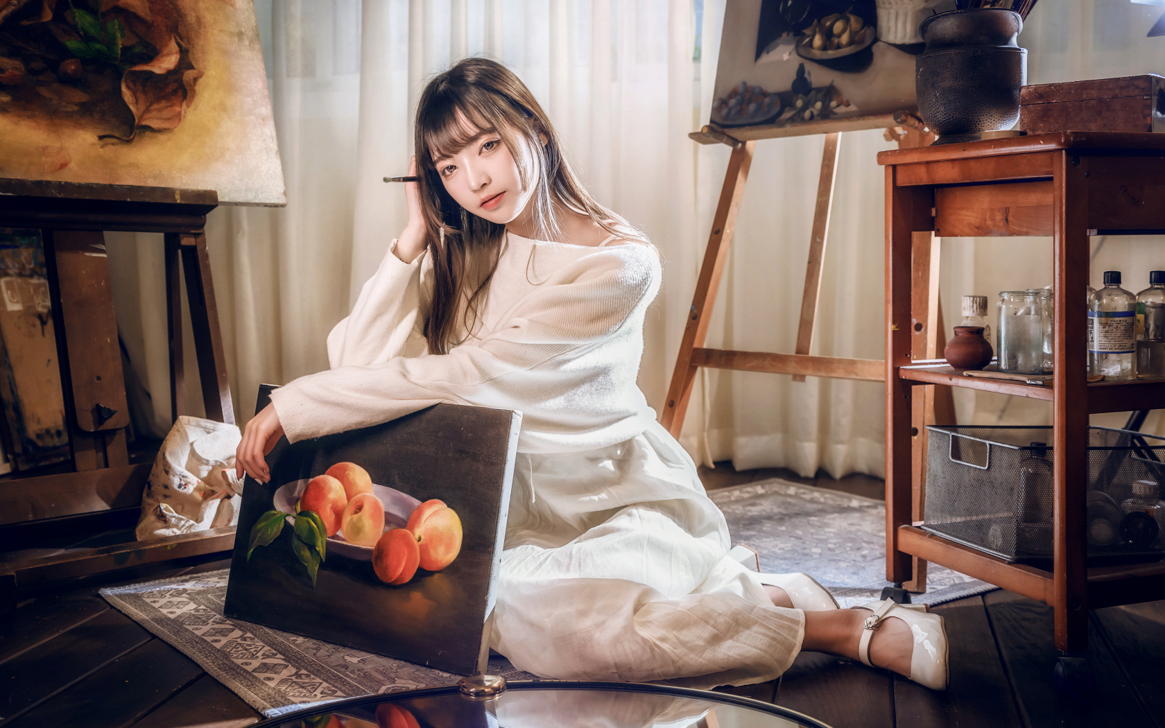 Девушка азиатка сидит с картиной на полу