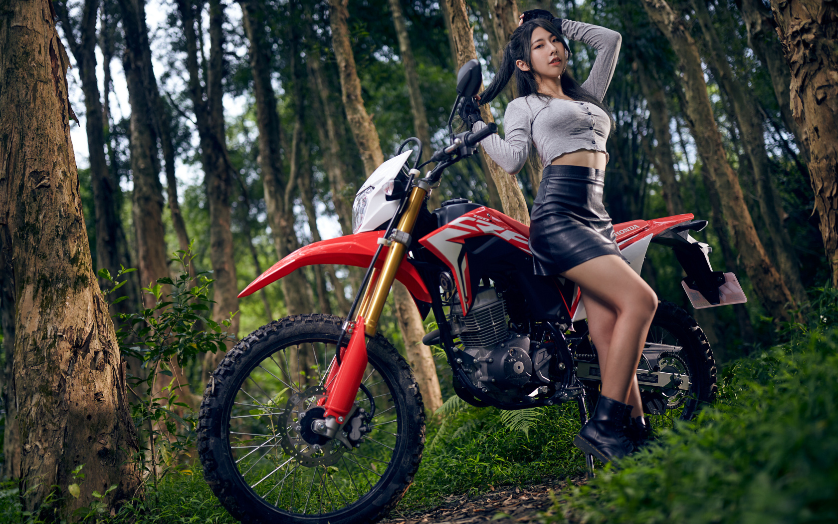 Девушка азиатка с мотоциклом в лесу