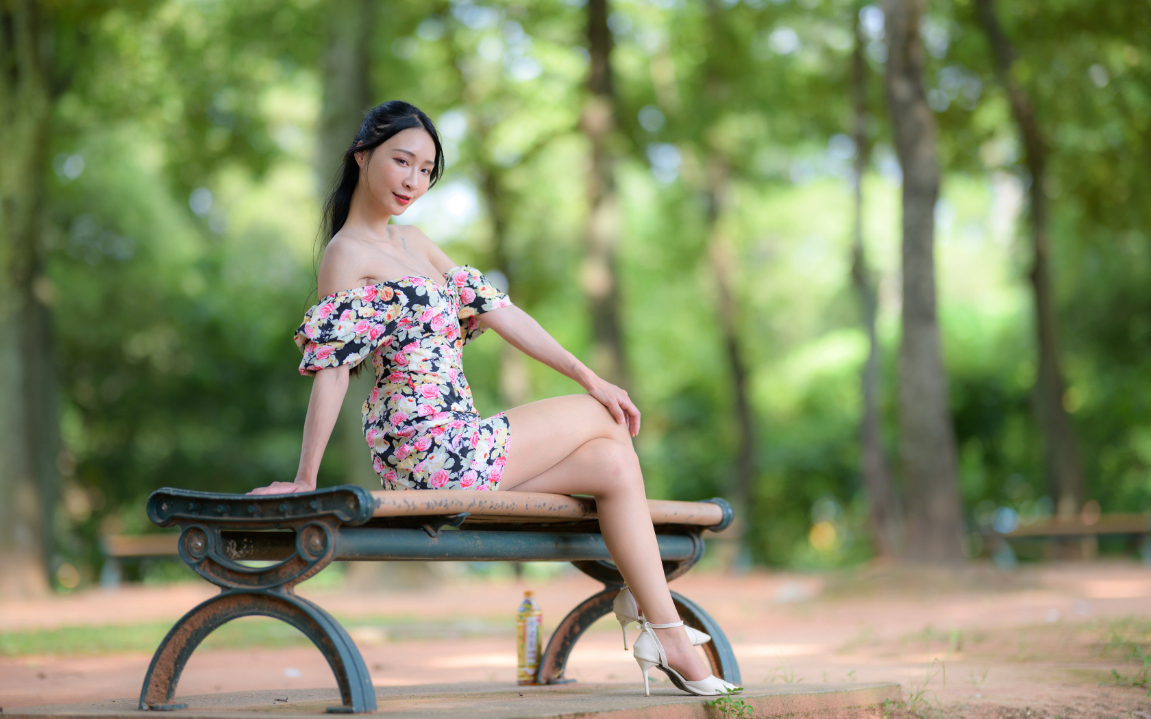 Милая девушка азиатка в платье сидит на лавке в парке