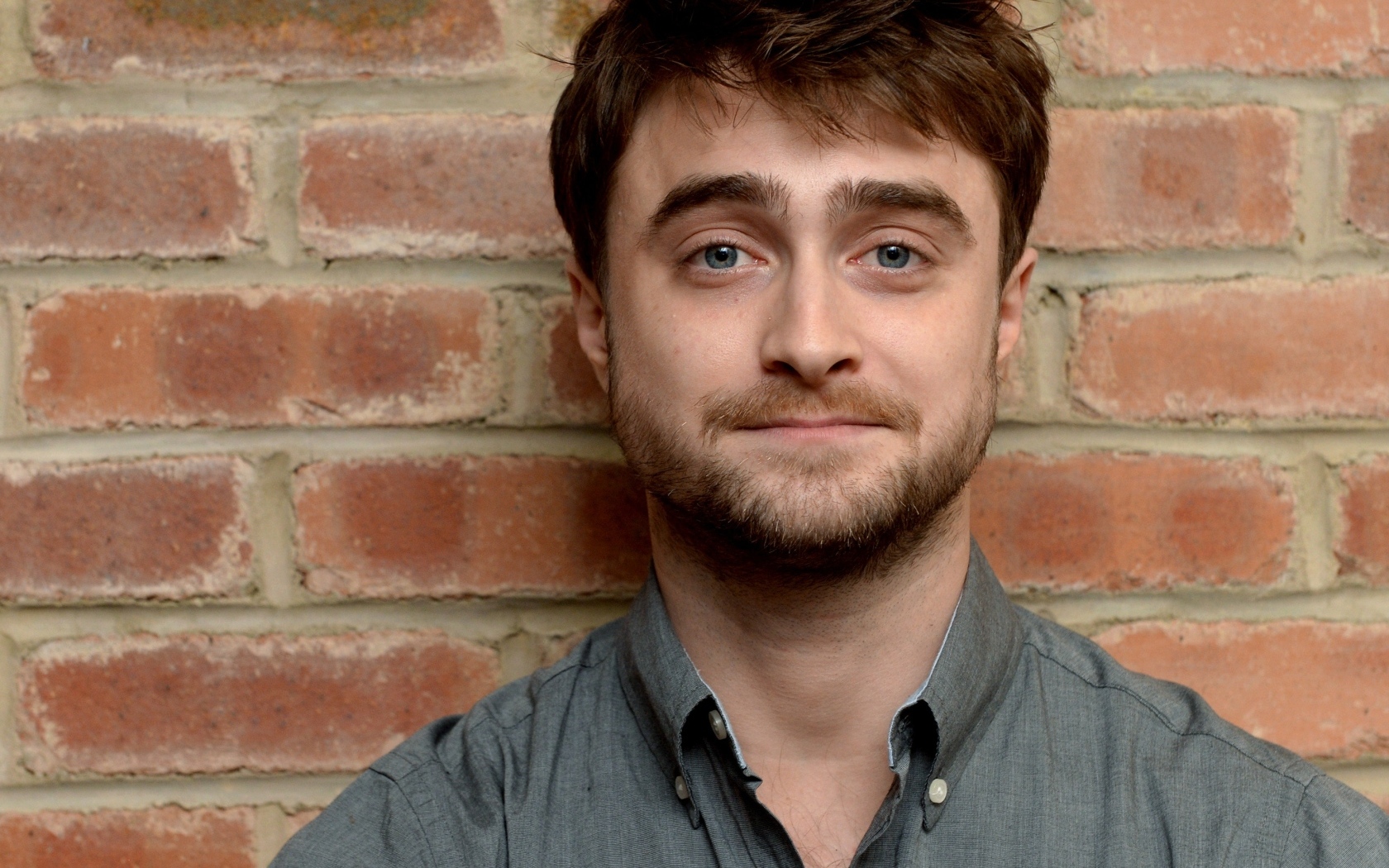 Актер Дэниел Рэдклифф стоит у стены