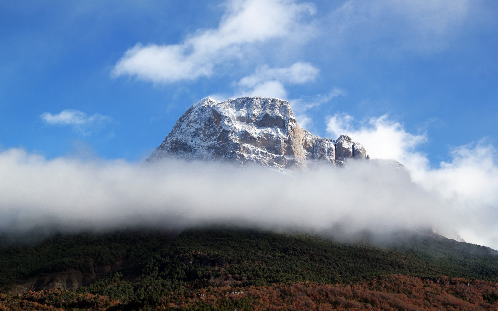 Заснеженная горная вершина в белых облаках
