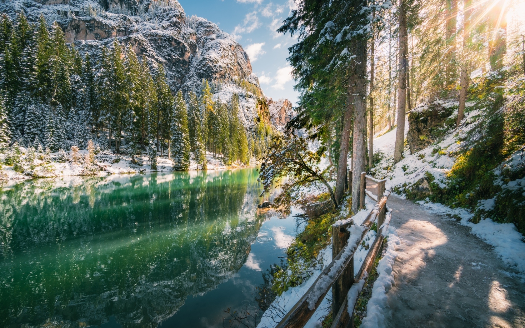 Заснеженная дорога у холодного горного озера в лесу