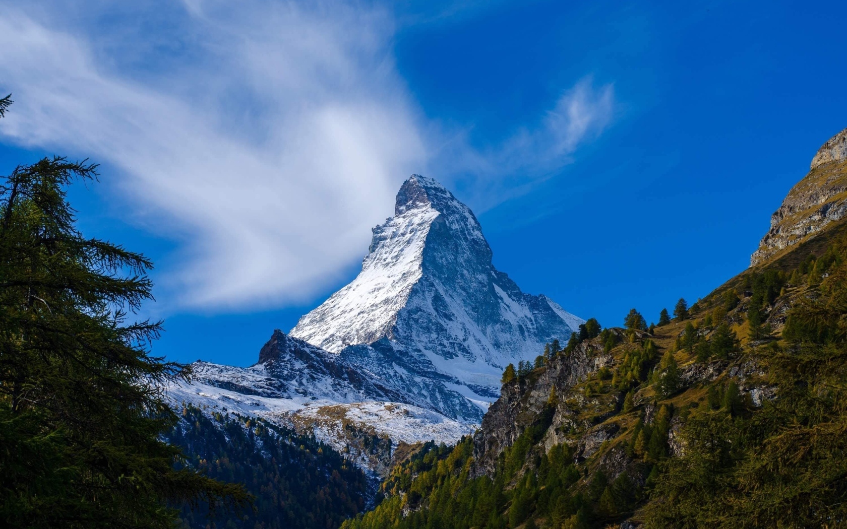 Вид на высокую заснеженную гору под голубым небом