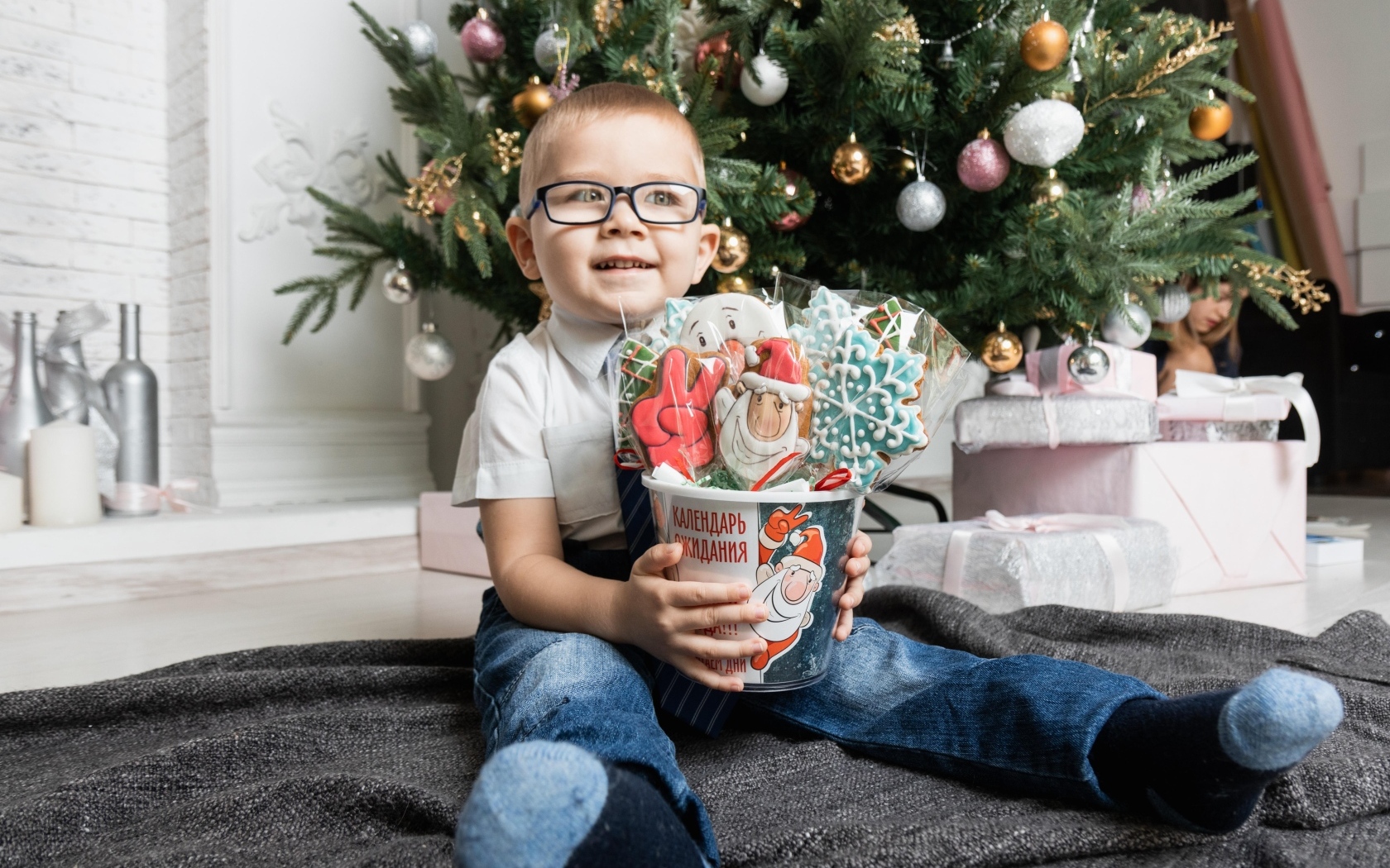 Маленький мальчик с печеньем сидит у ели