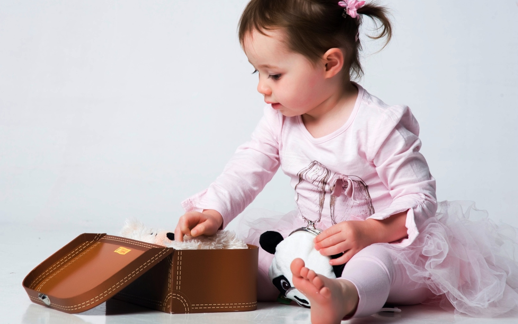 Девочка в розовом наряде с маленьким чемоданом