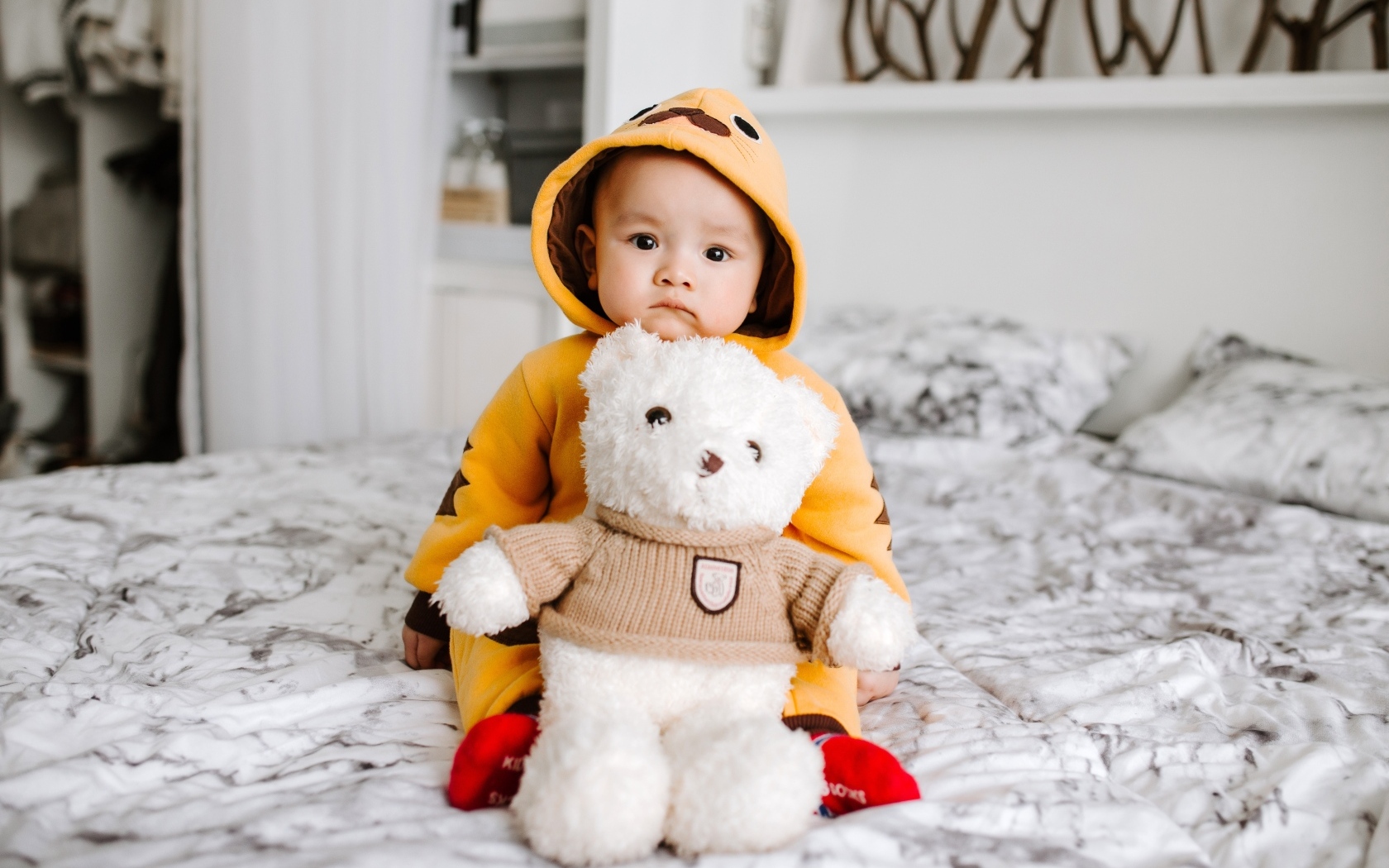 Маленький ребенок с игрушкой на кровати 