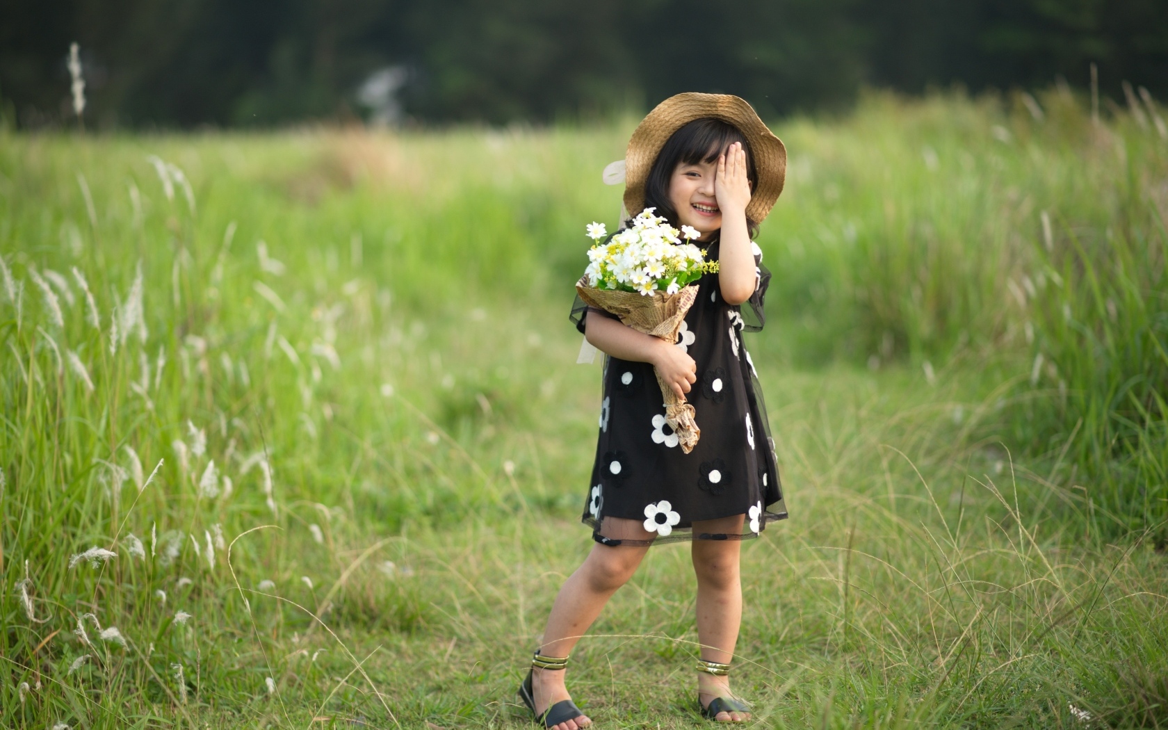 Маленькая девочка с букетом цветов на зеленой траве