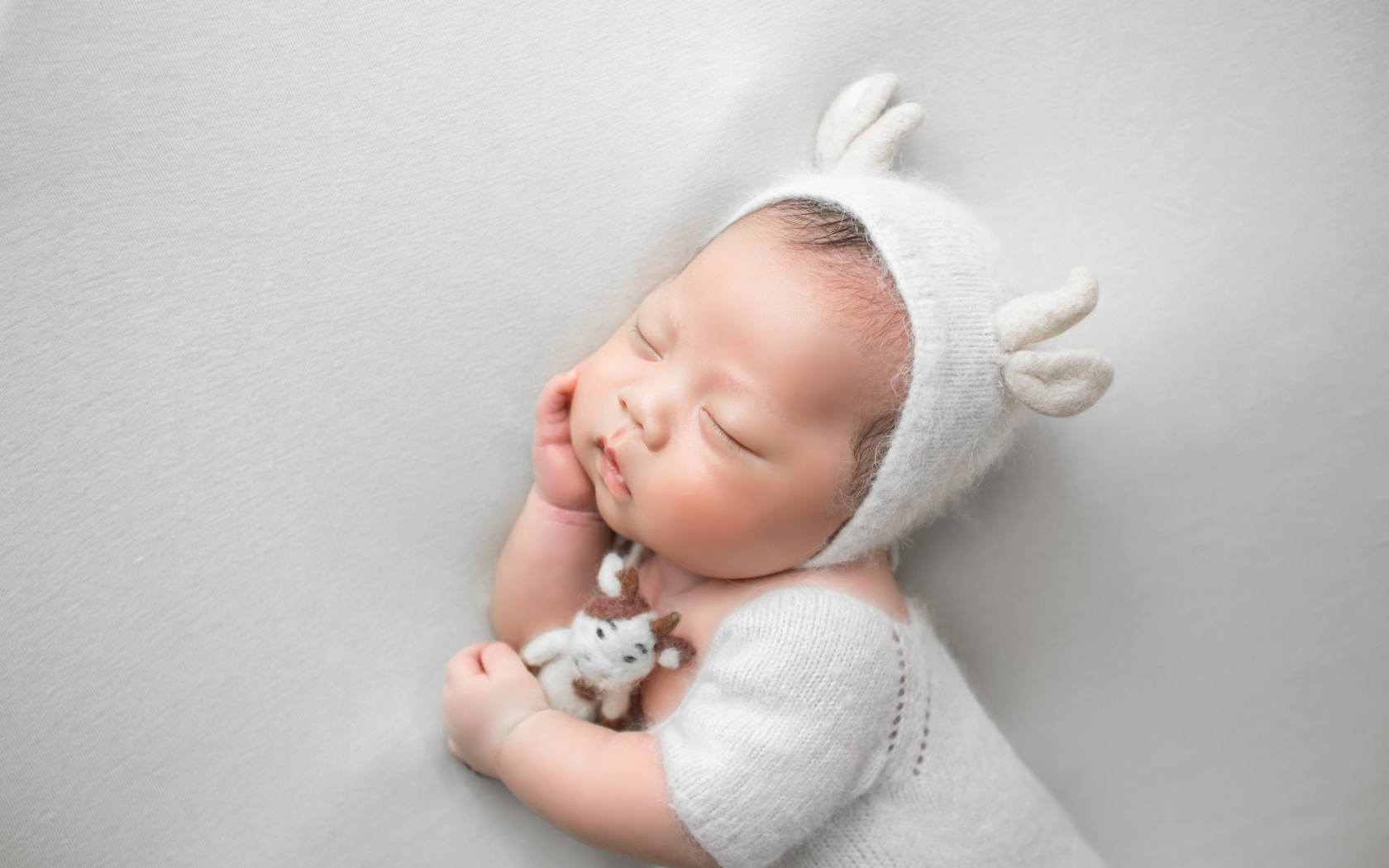 Маленький спящий малыш на сером фоне