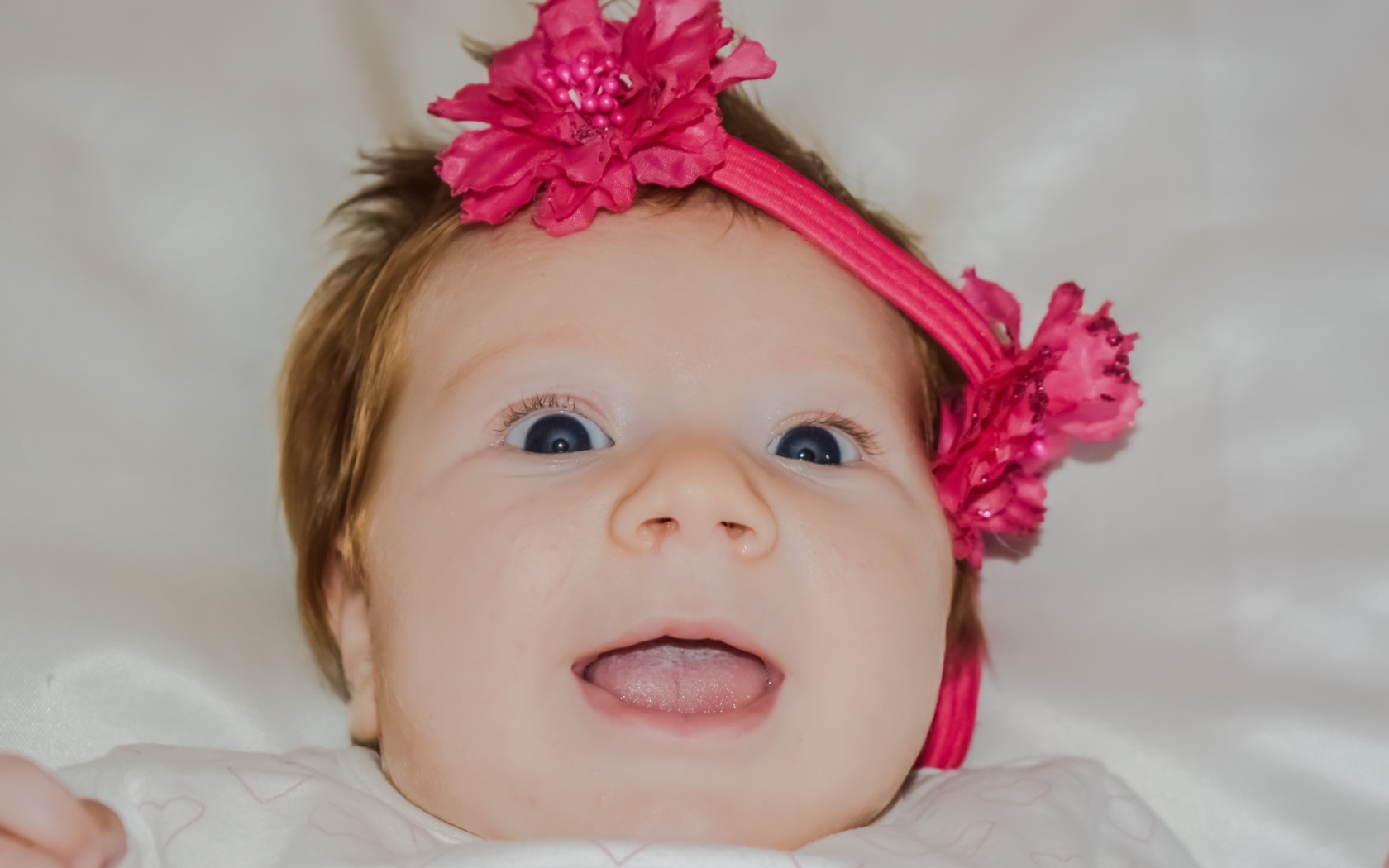 Улыбающаяся маленькая девочка с цветком на голове
