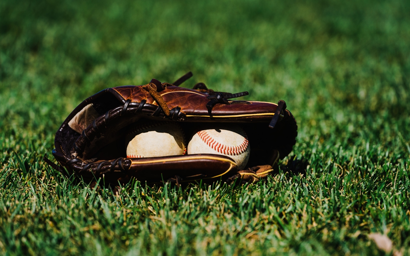 Бейсбольная перчатка и мячи на зеленой траве