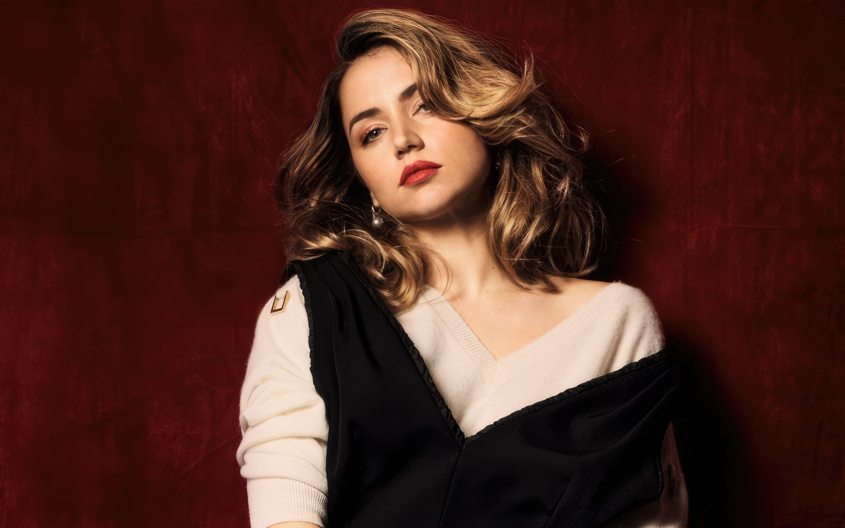 Милая актриса Ана де Армас стоит у красной стены