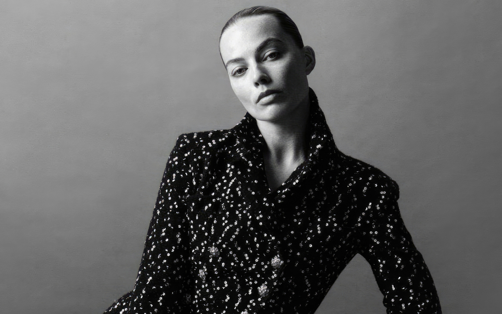 Грустная Марго Робби в блестящем пиджаке на сером фоне