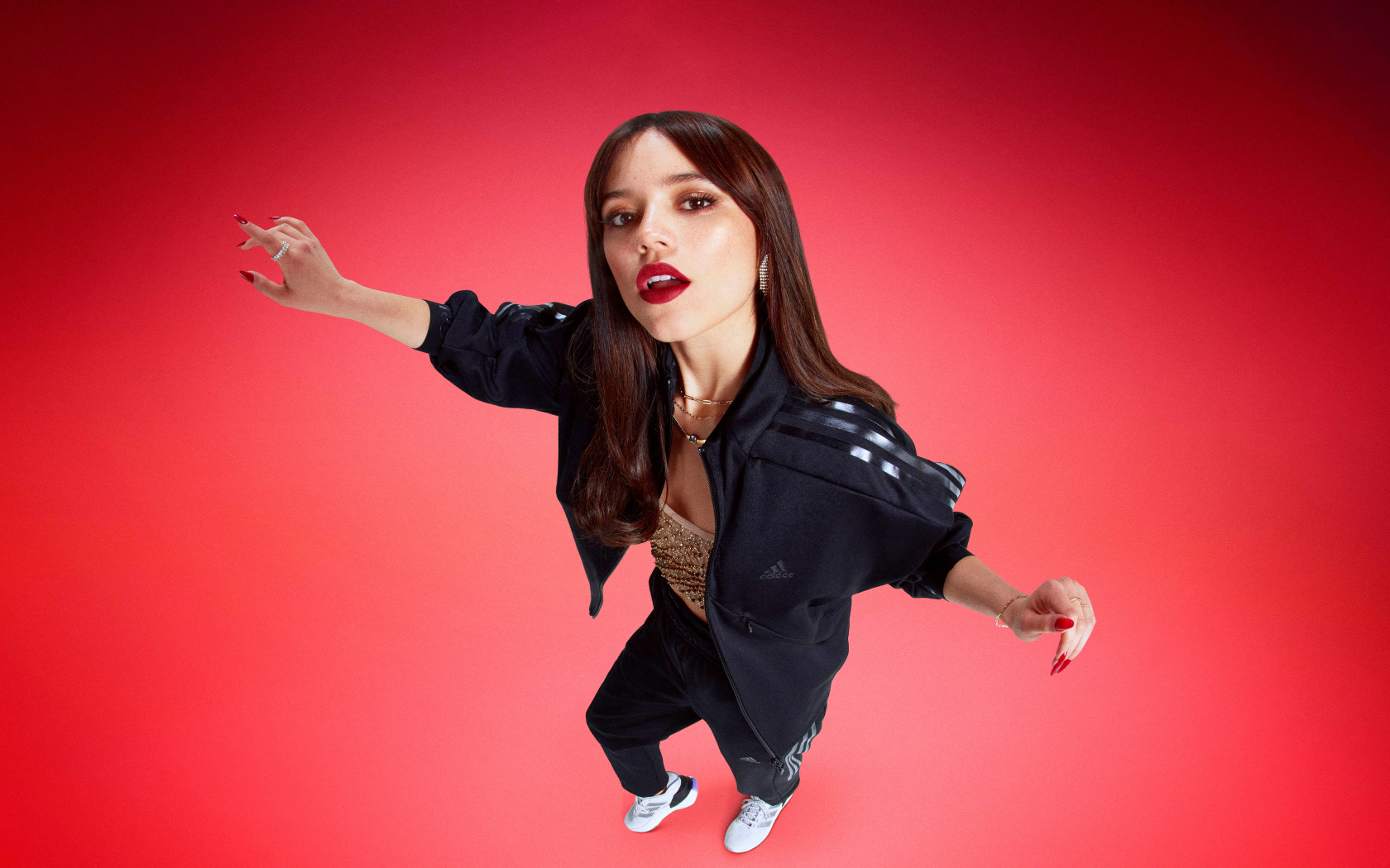 Молодая девушка актриса Дженна Ортега в спортивном костюме на красном фоне