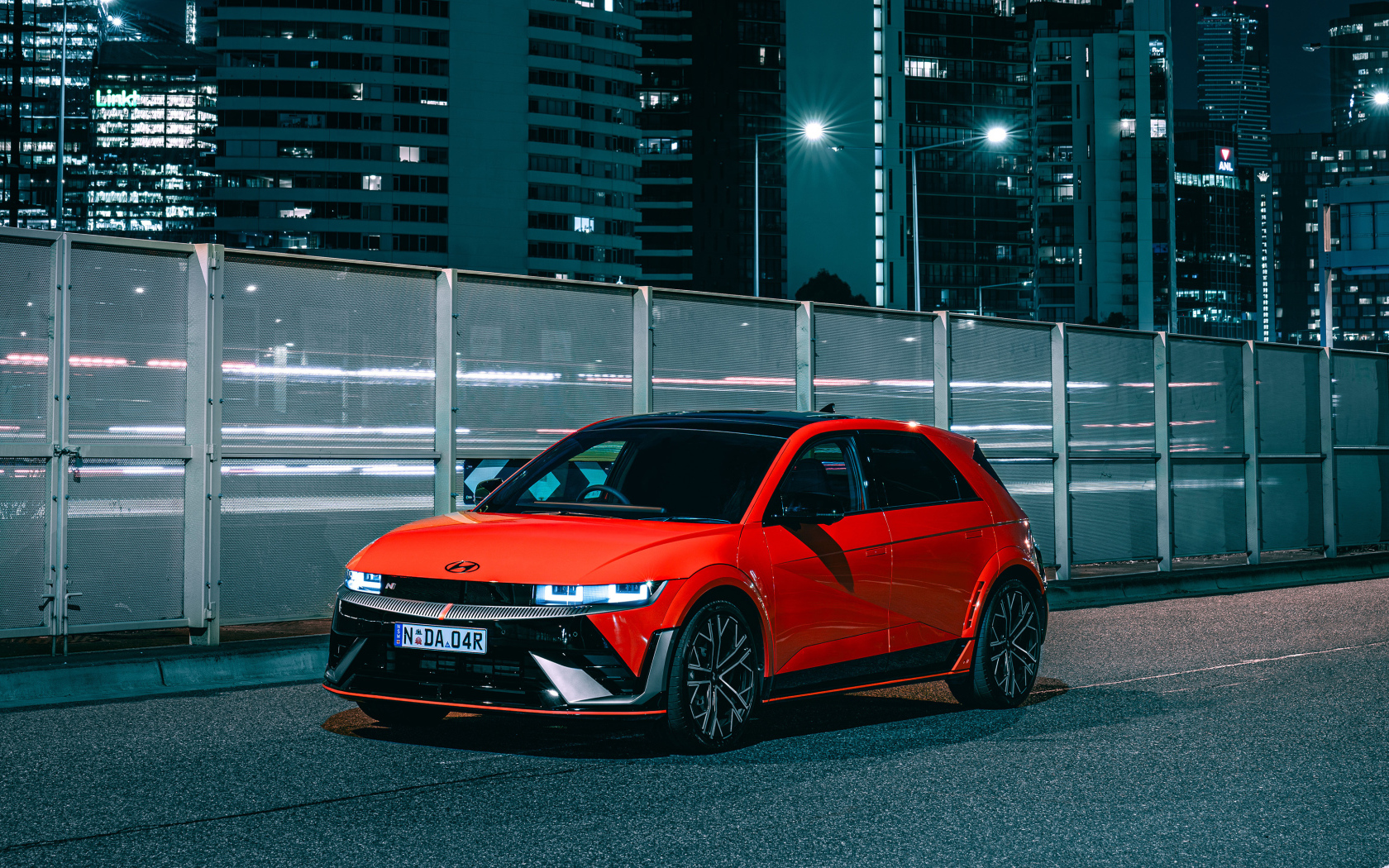 Красный автомобиль Hyundai IONIQ 5 N 2024 года у забора