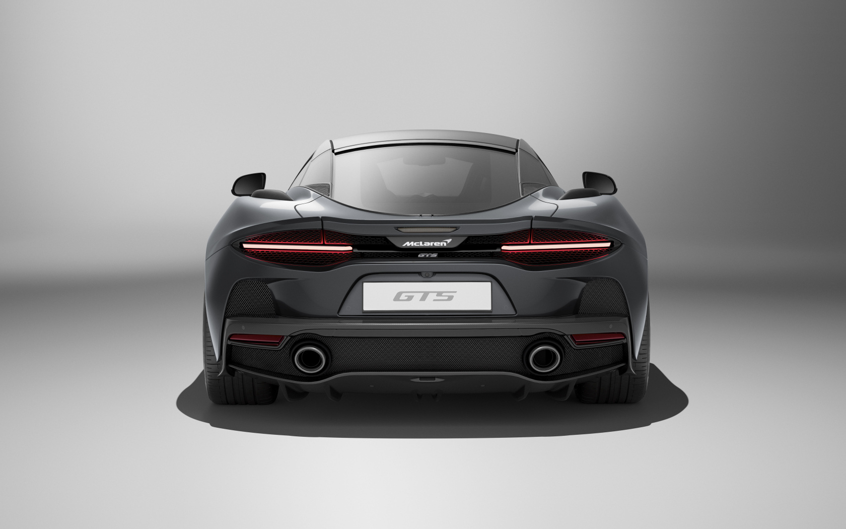 Вид сзади на автомобиль McLaren GTS на сером фоне