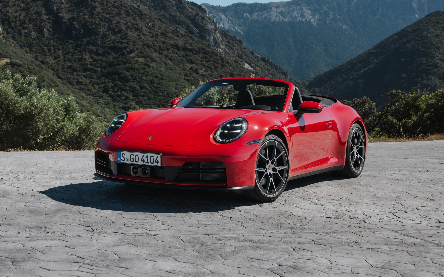 Красный Porsche 911 Carrera Cabriolet 2024  года на фоне гор
