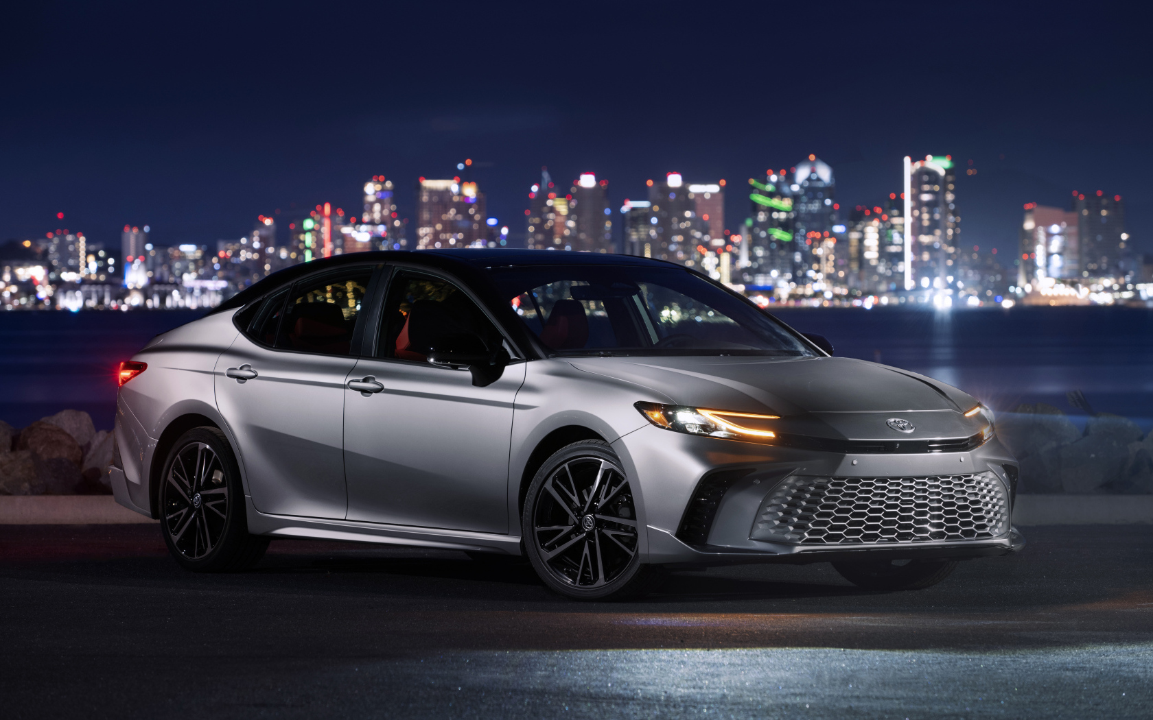 Новый автомобиль Toyota Camry XSE HEV AWD 2025 года на фоне города