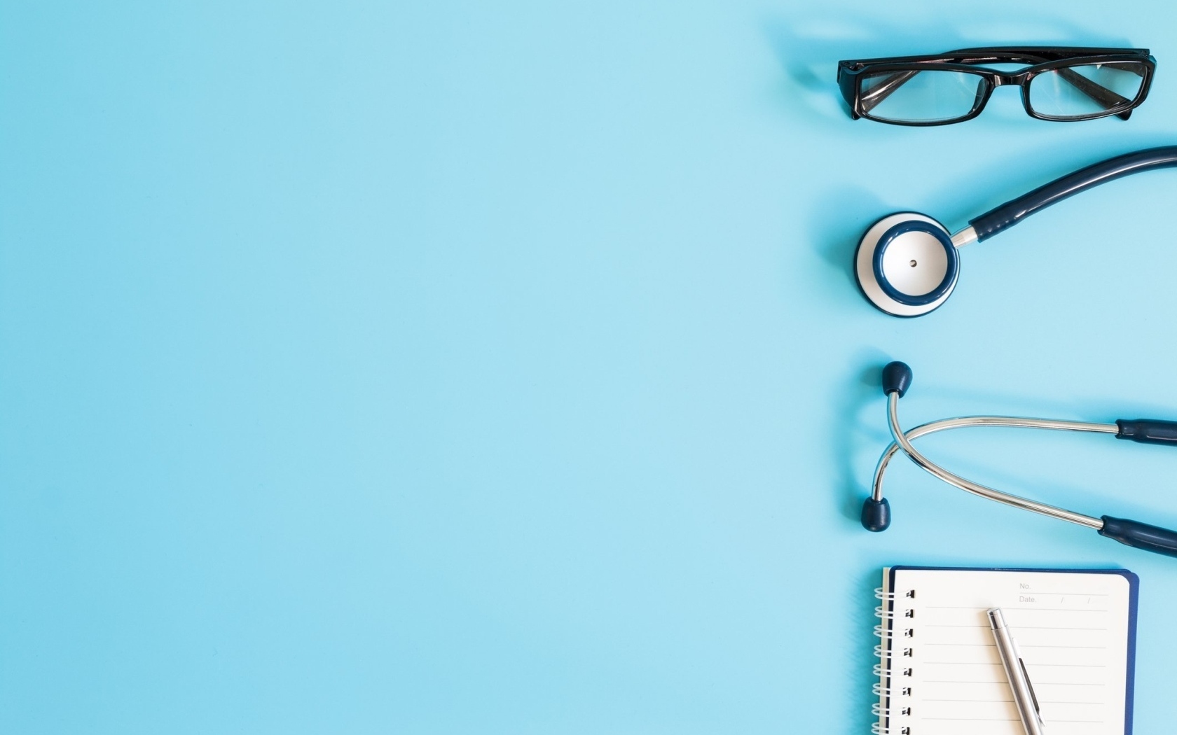 Стетоскоп, очки и блокнот на голубом фоне