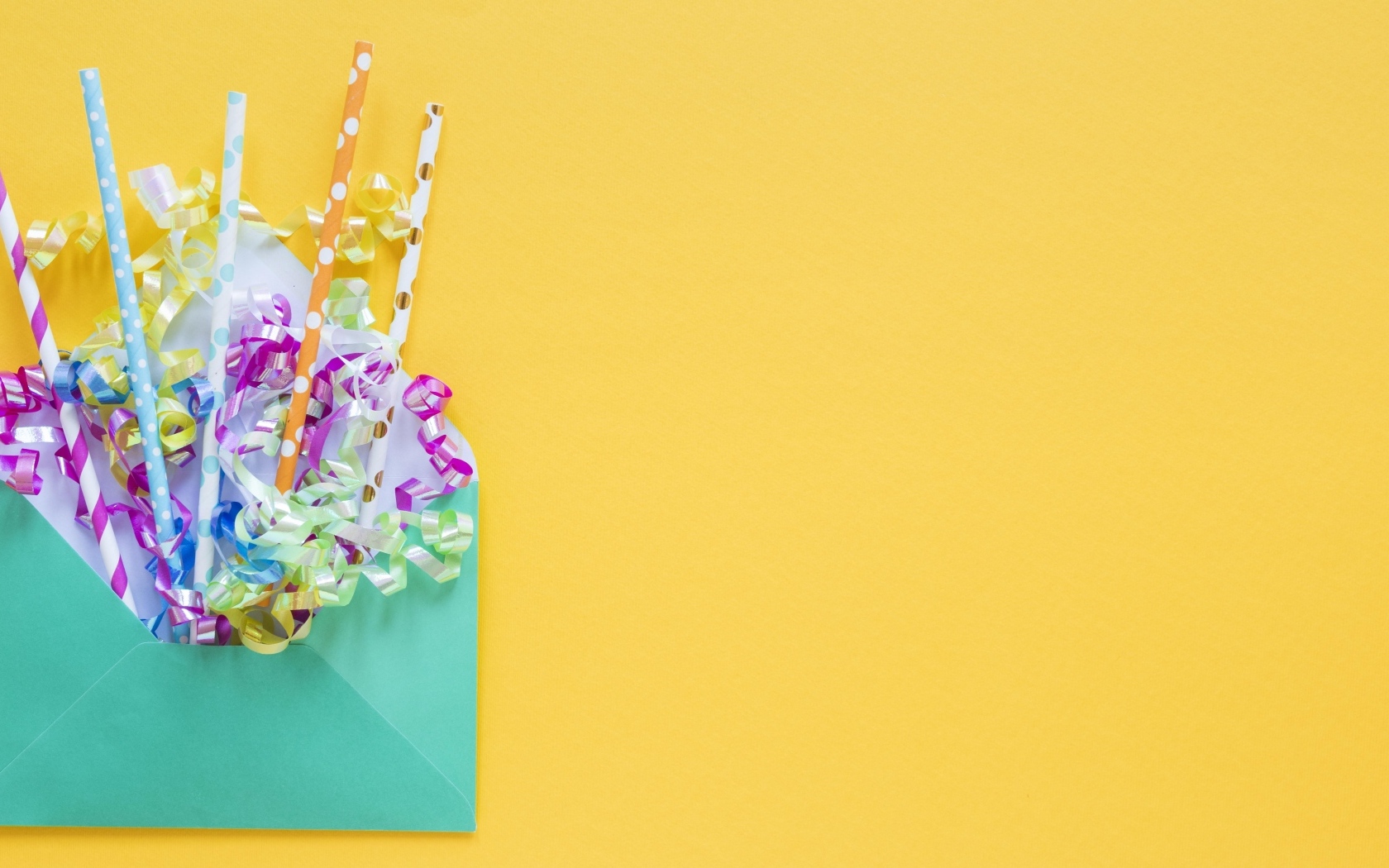 Конверт с трубочками и лентами на желтом фоне
