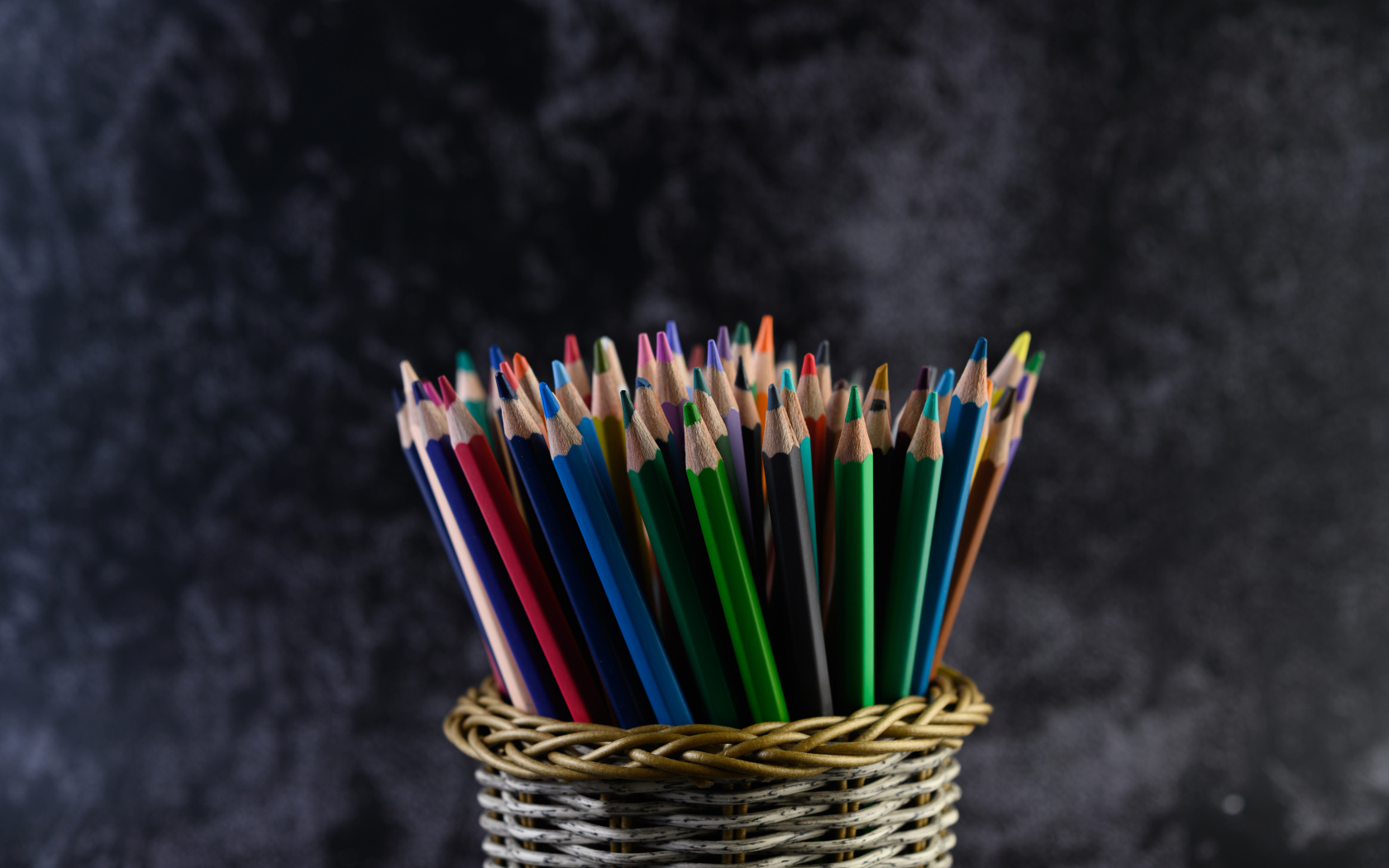 Разноцветные карандаши в стакане на сером фоне