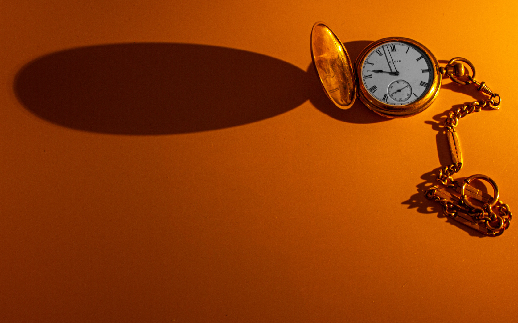 Тень от карманных часов на оранжевом фоне