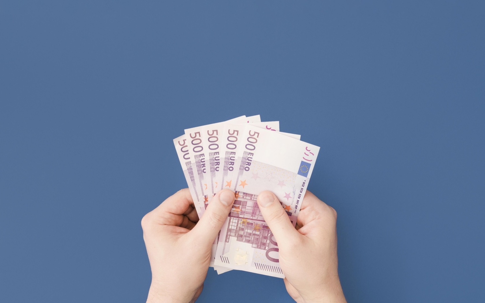 Купюры в пятьсот евро в руках на синем фоне