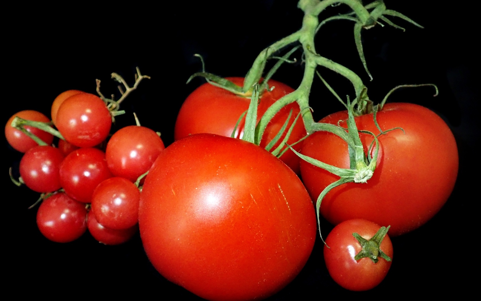 Большие помидоры и помидоры черри на черном фоне