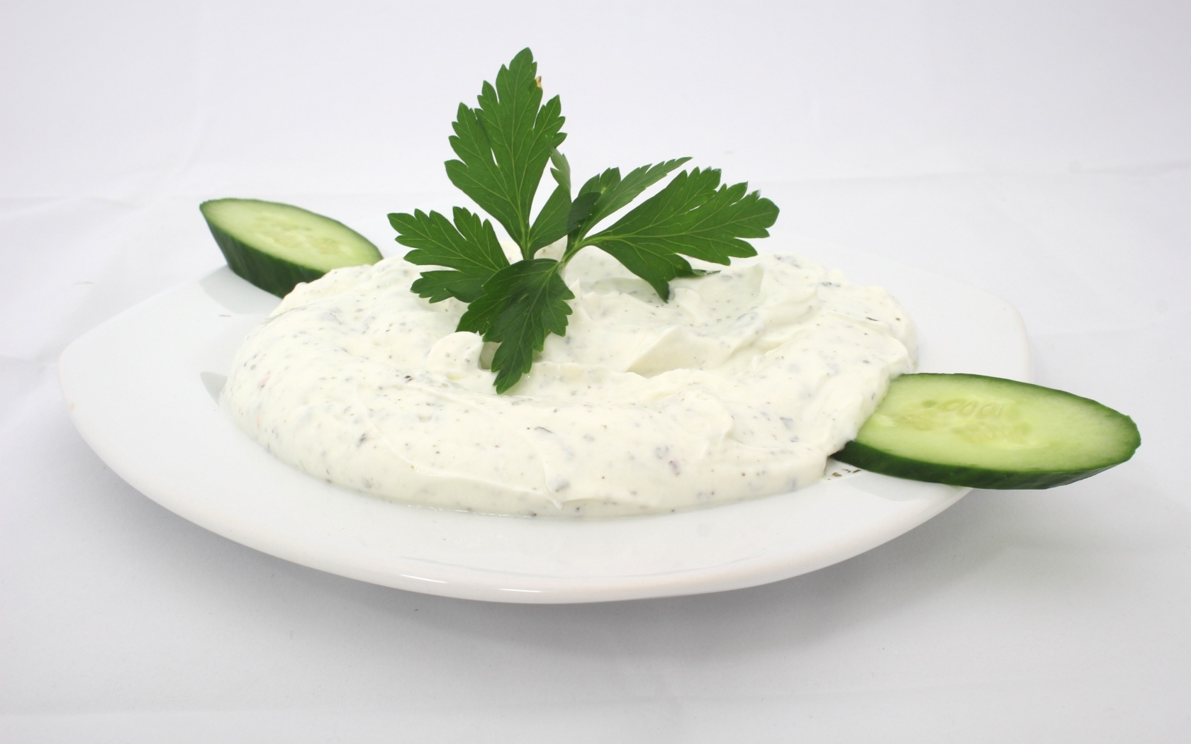 Соус на тарелке со свежими огурцами