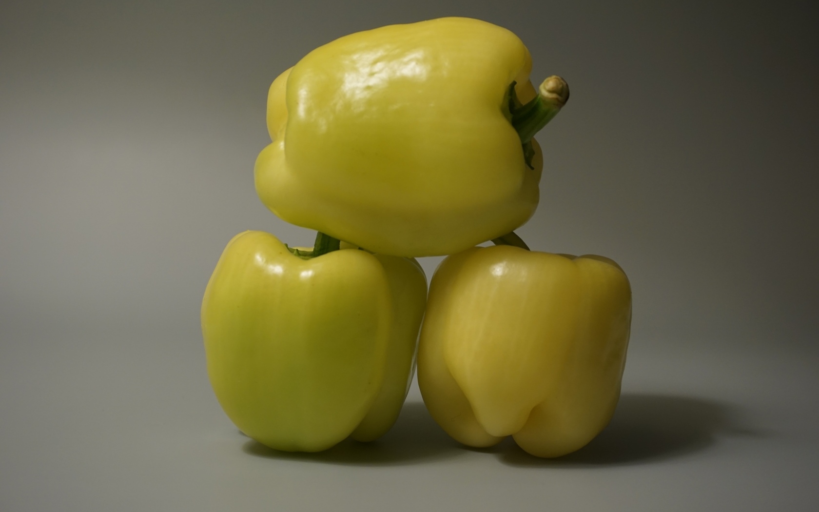 Три желтых перца на сером фоне