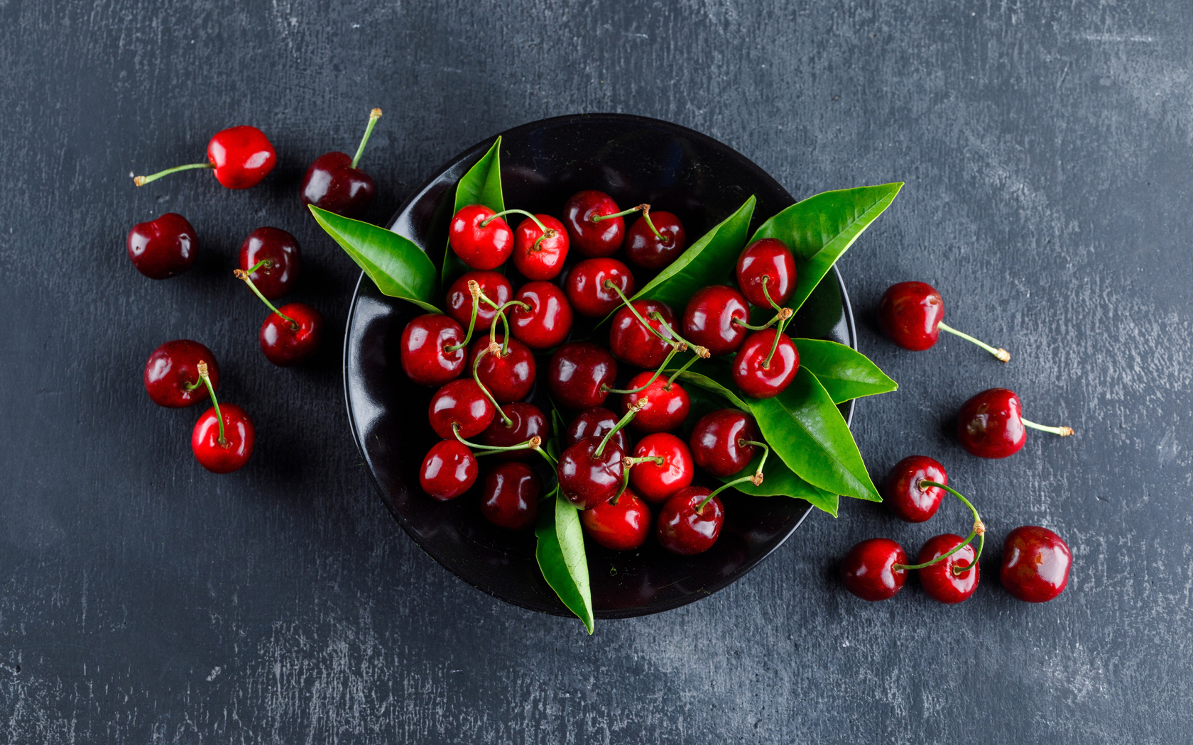 Черная  тарелка с красными ягодами черешни