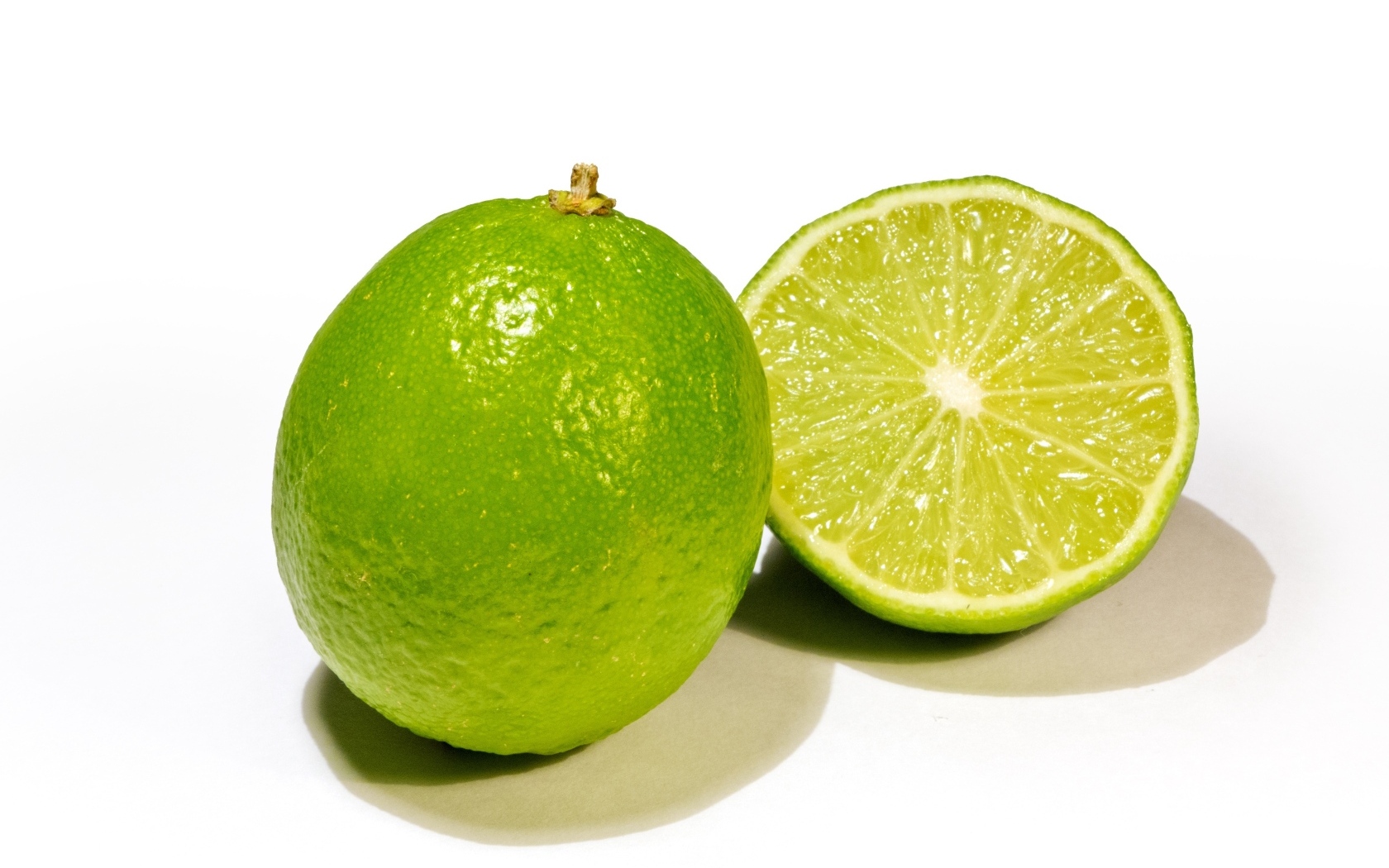Разрезанный зеленый лайм на белом фоне