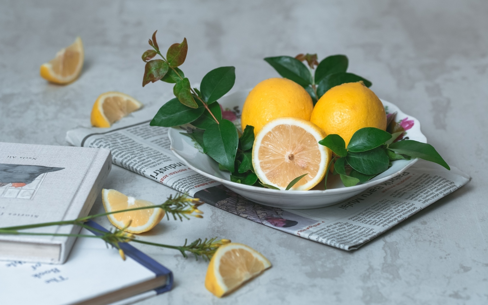 Лимоны на тарелке с зелеными листьями