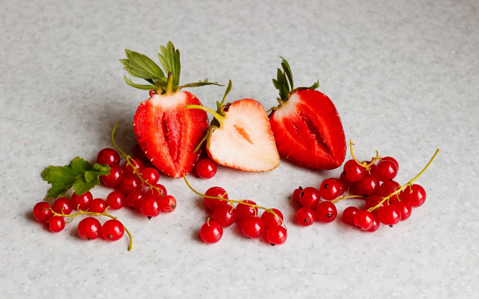 Ягоды клубники с красной смородиной на сером столе