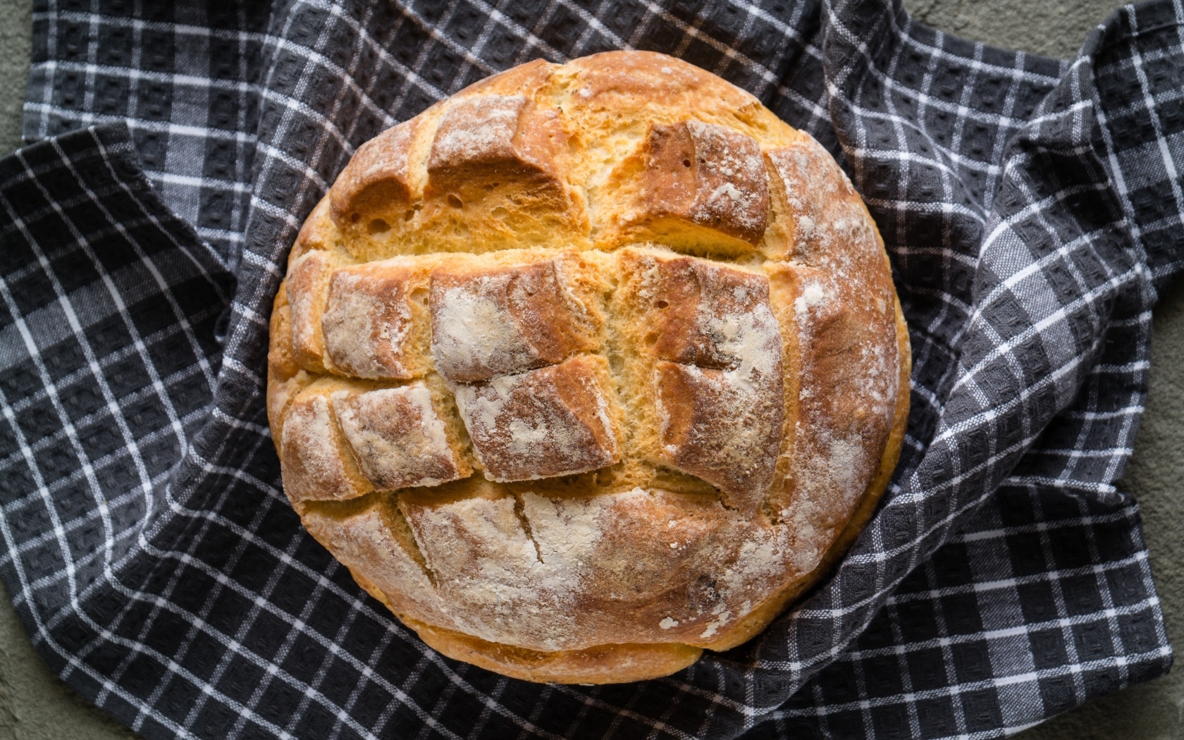 Круглый хрустящий хлеб на столе со скатертью