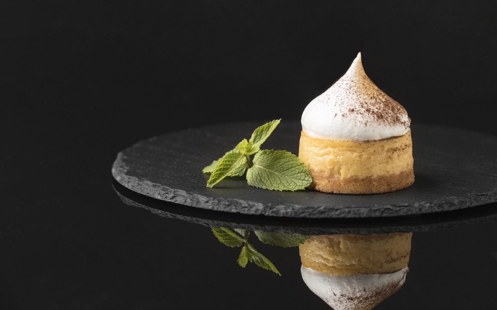 Десерт с кремом и листьями мяты на черном фоне