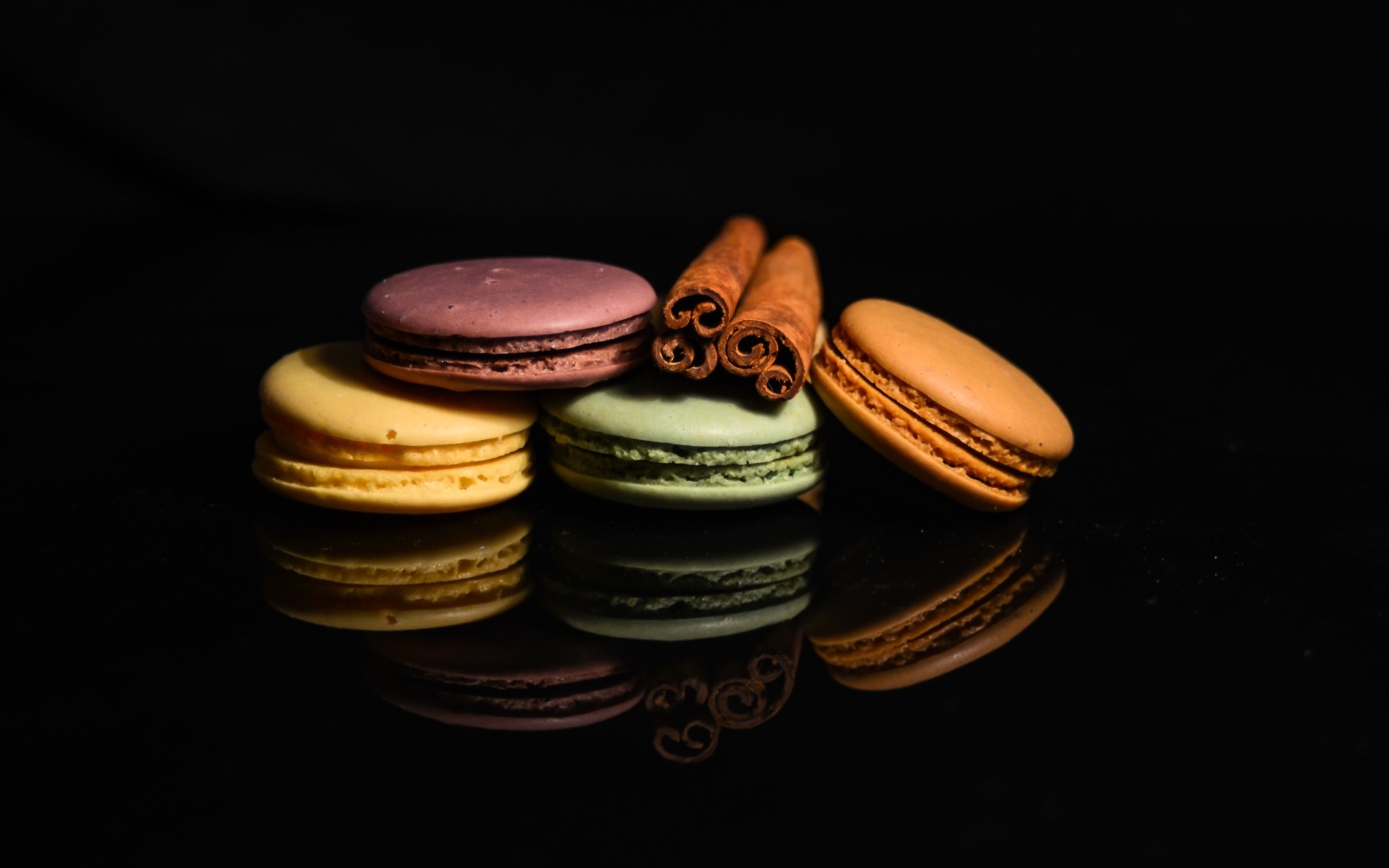 Десерт макарон с корицей на черном фоне