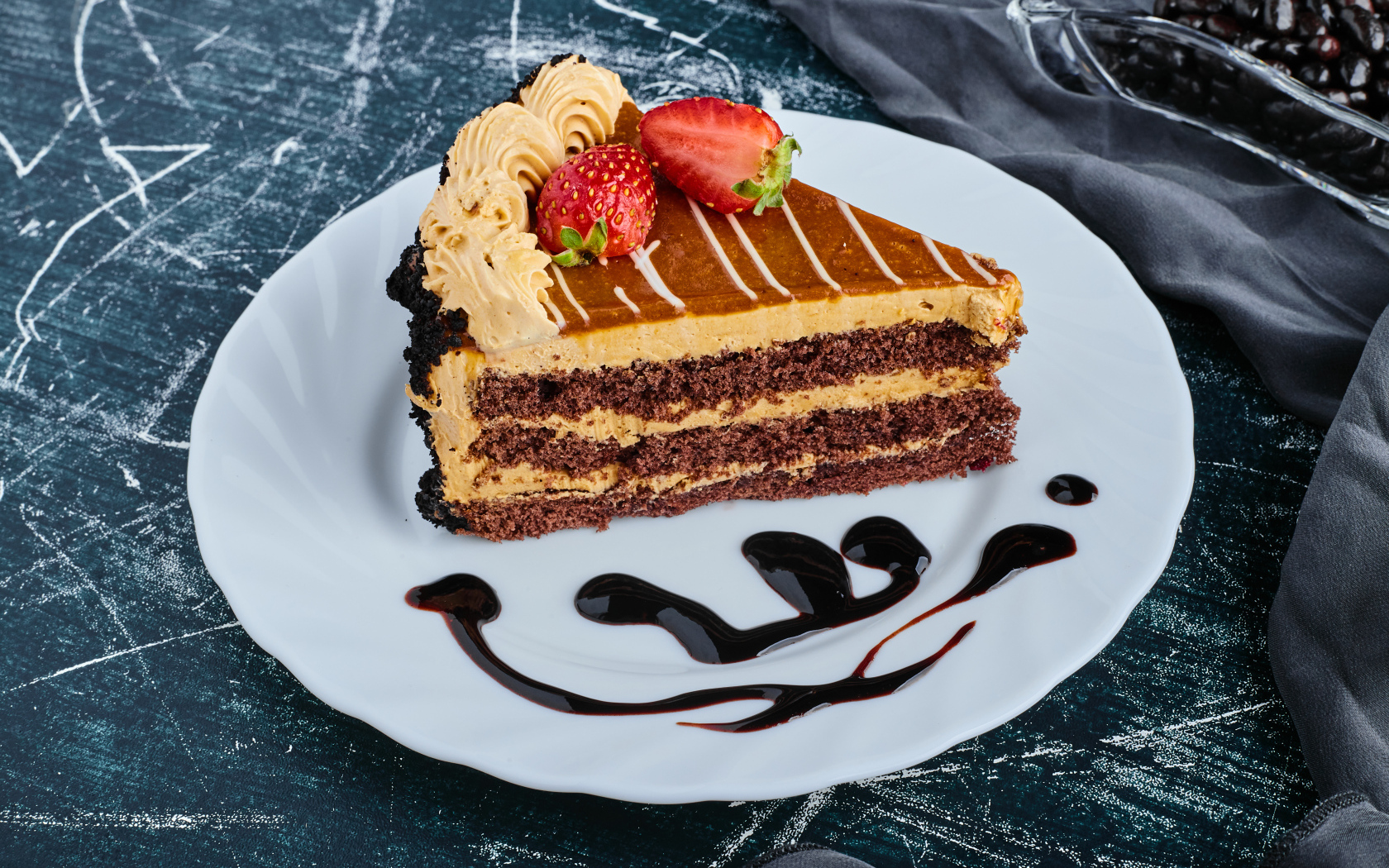 Кусок торта с клубникой на большой белой тарелке