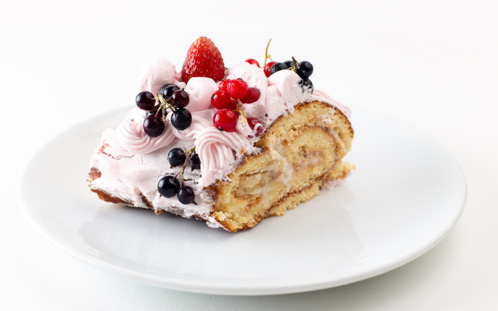Ломтик сладкого рулета с ягодами и кремом