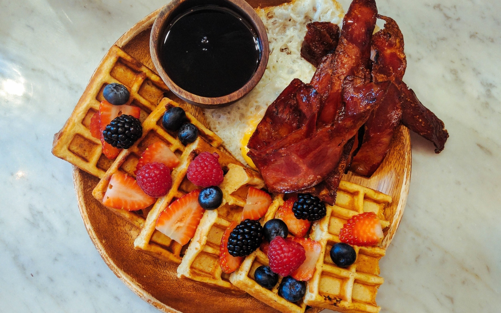 Сладкие вафли с ягодами на тарелке с беконом