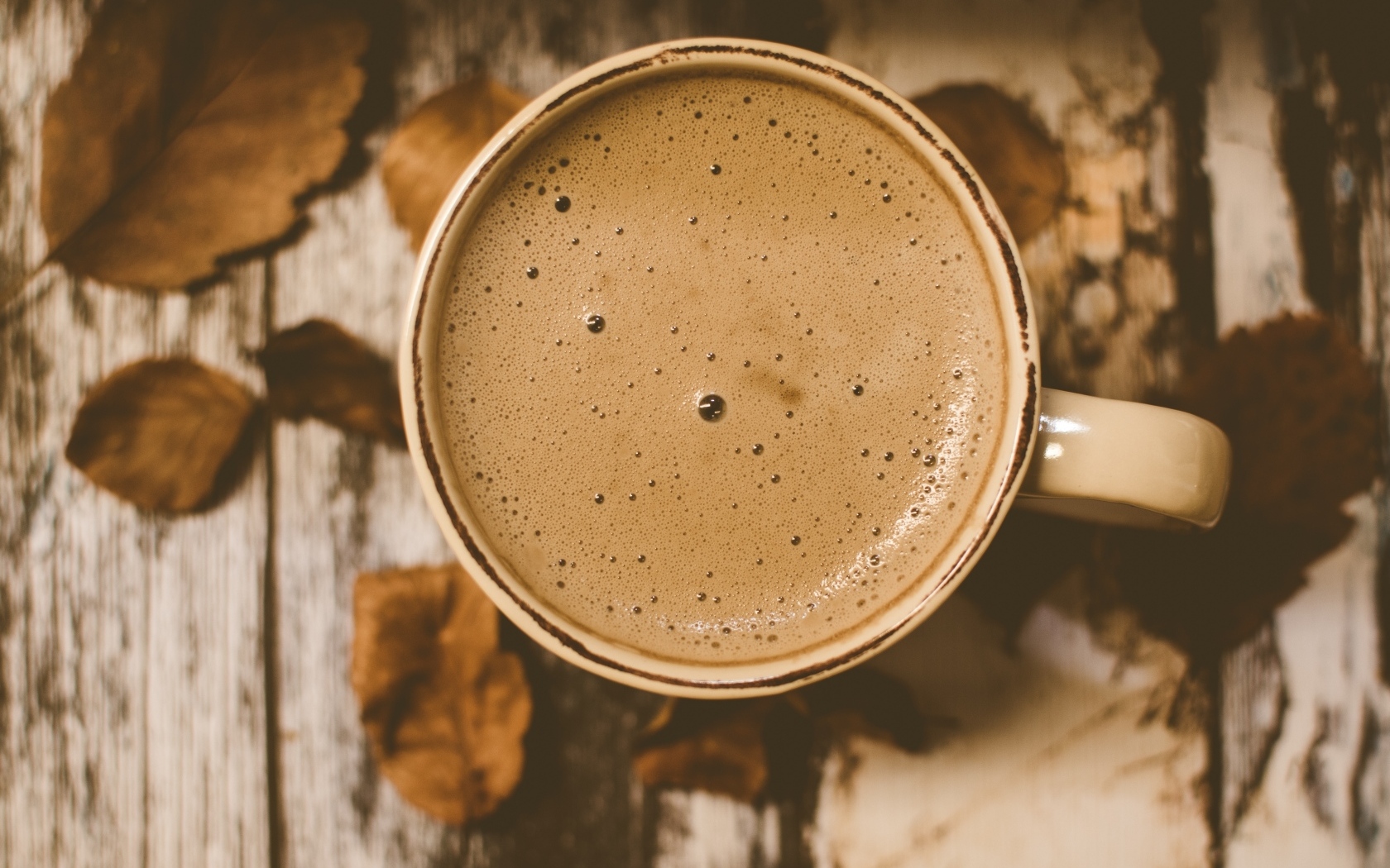 Чашка ароматного кофе с пенкой на столе с листьями