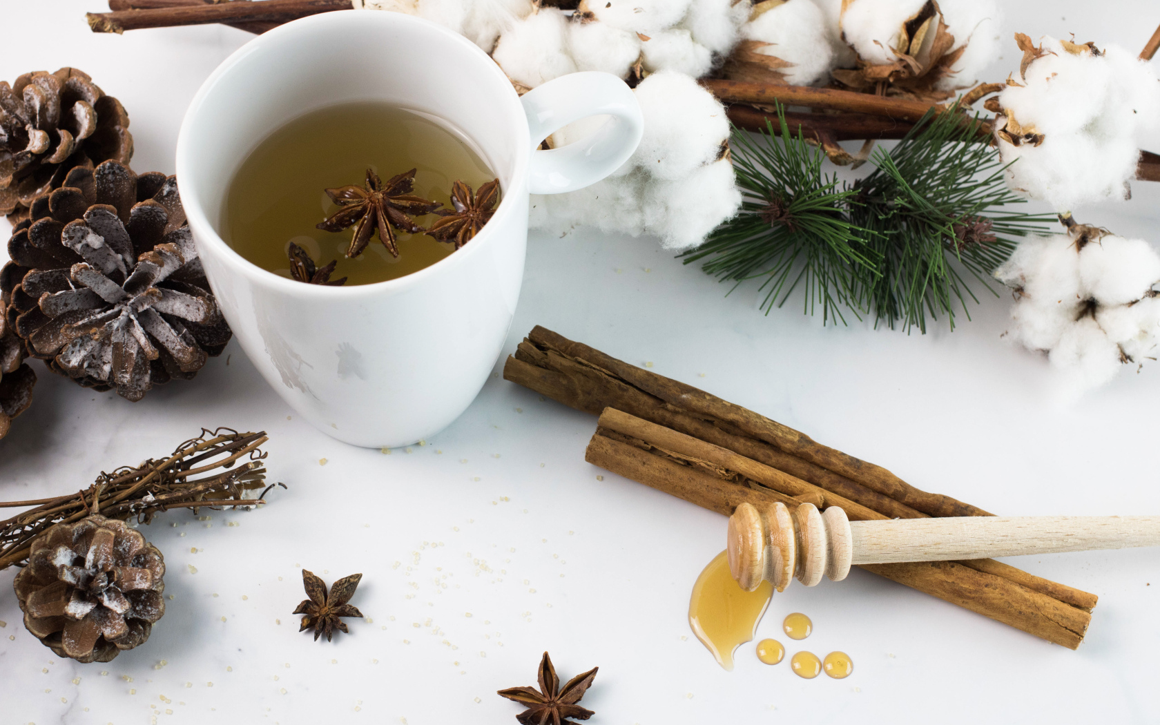 Чашка чая со специями на столе с хлопком и шишками