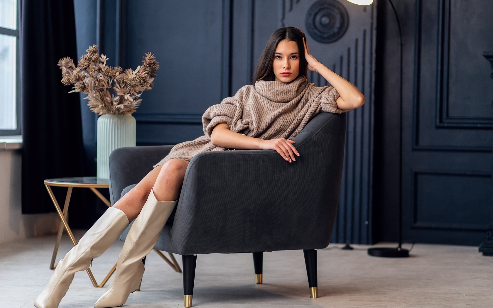 Красивая брюнетка в сапогах сидит в кресле