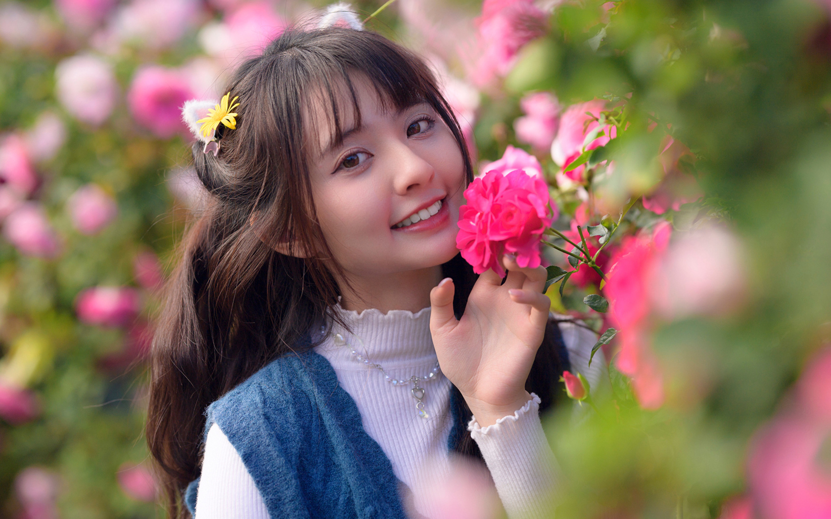 Красивая улыбающаяся азиатка с розовым цветком розы
