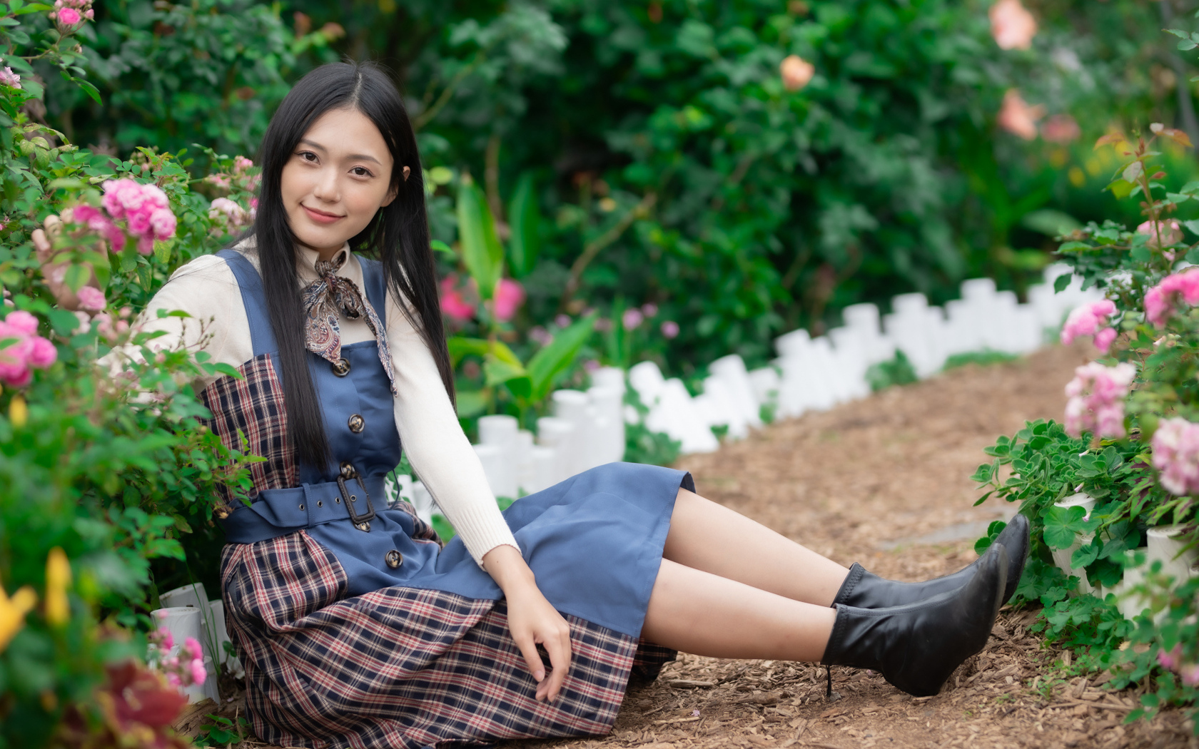 Настоящая молодая азиатка сидит на земле у клумбы